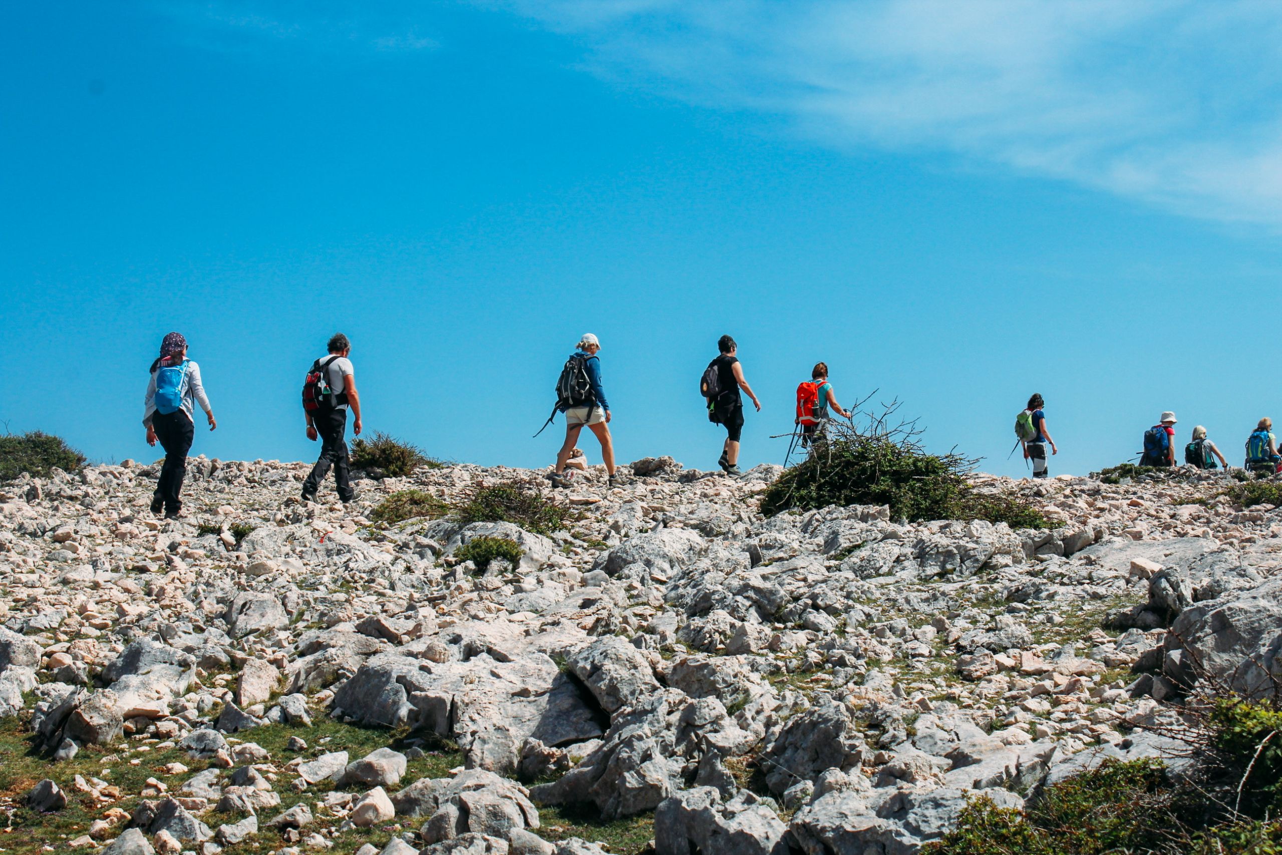 Gruppo si persone in cammino su terreno roccioso, viaggio di gruppo a piedi, trekking nell'isola di Krk